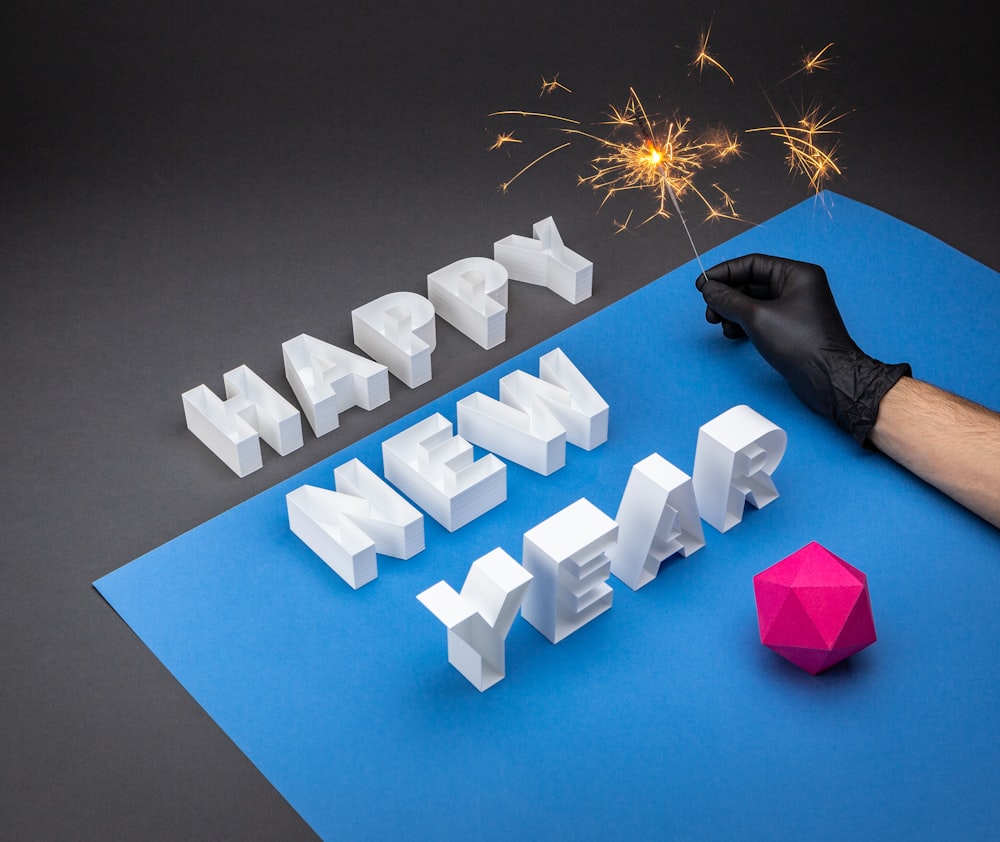 a person holding a sparkler next to a happy new year sign