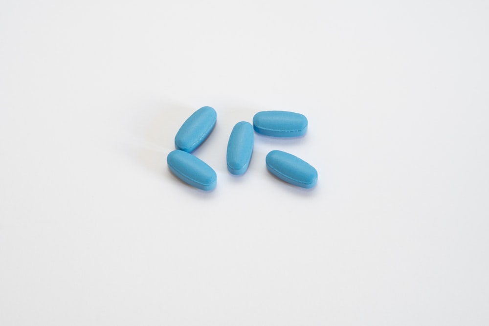 a group of blue pills sitting on top of a white table