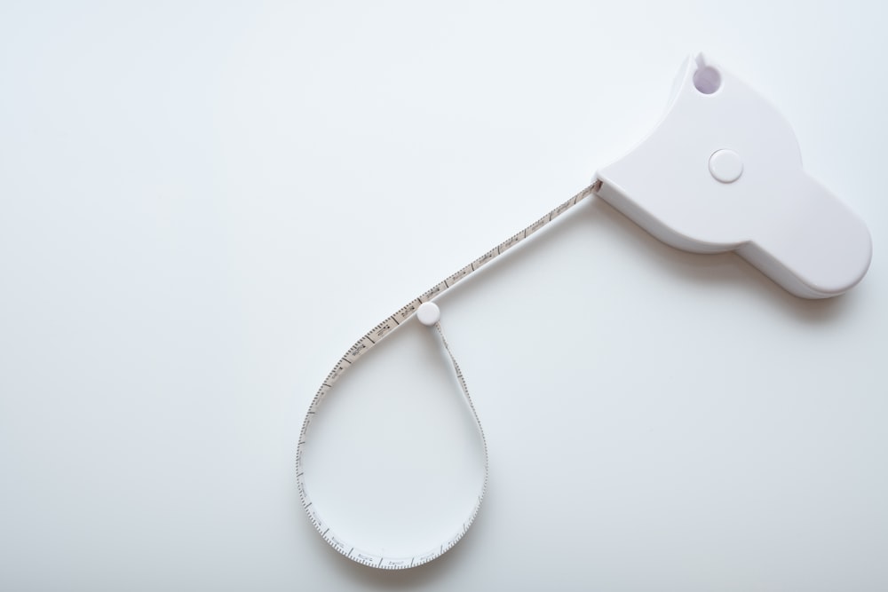 un objet blanc auquel un ruban à mesurer est attaché