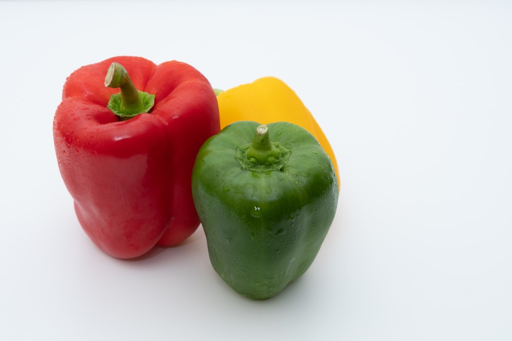 a green pepper, a red pepper and a yellow pepper