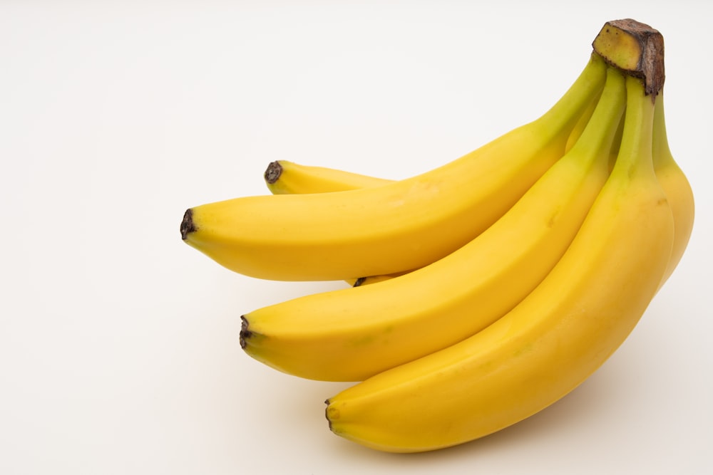 un mazzo di banane seduto sopra un tavolo bianco