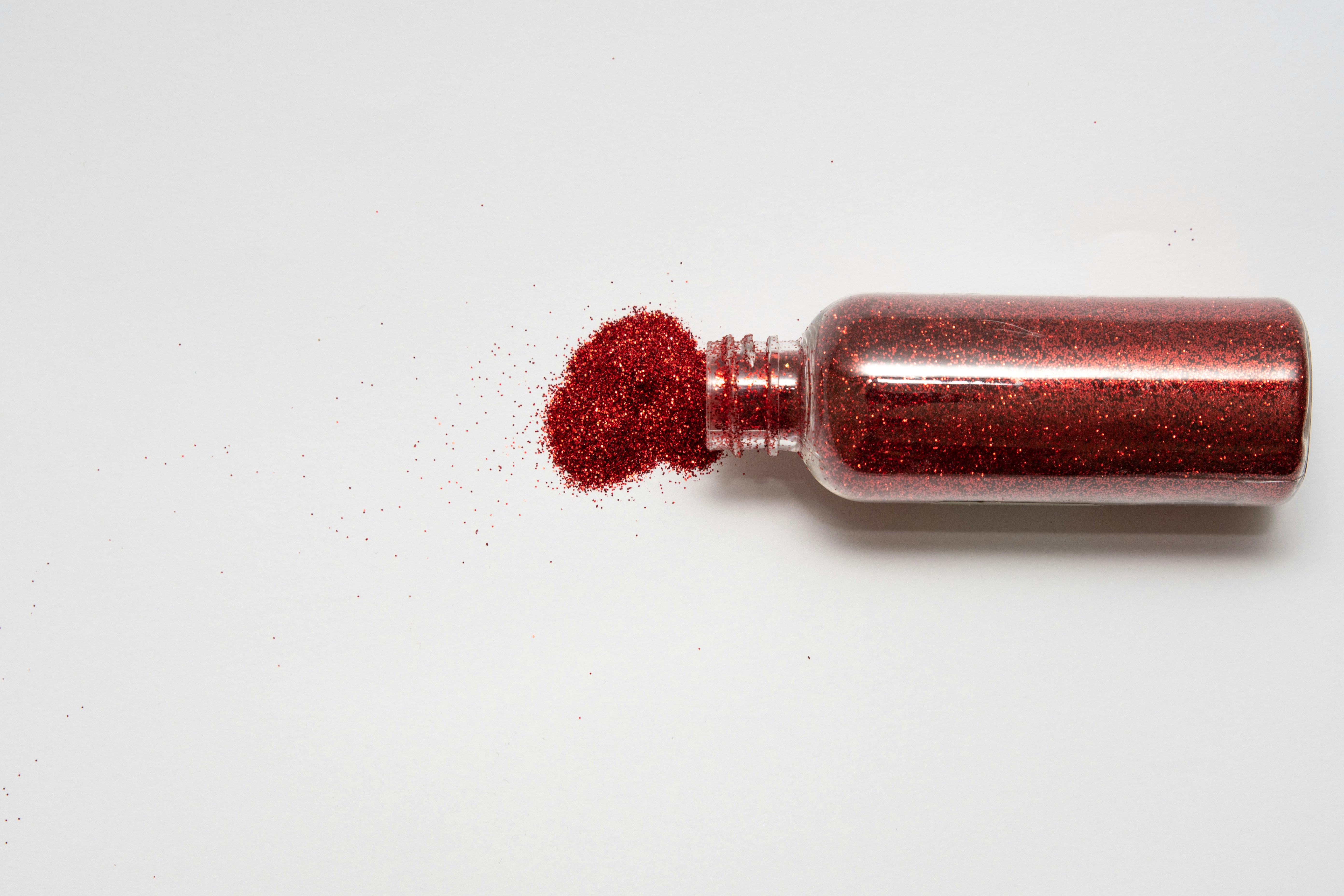a bottle of red glitter sitting on top of a white table