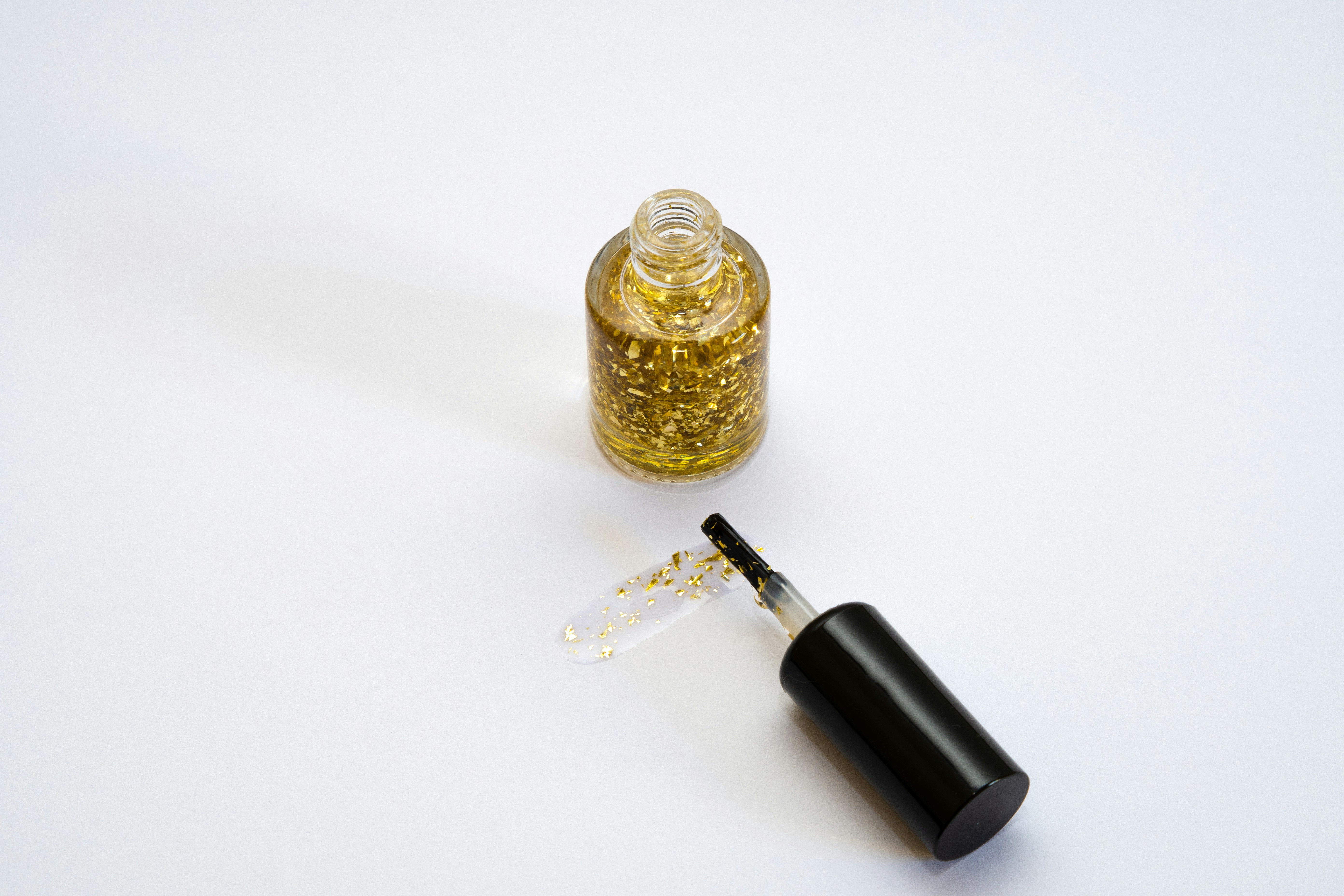 yellow nail polish with glitter on white background