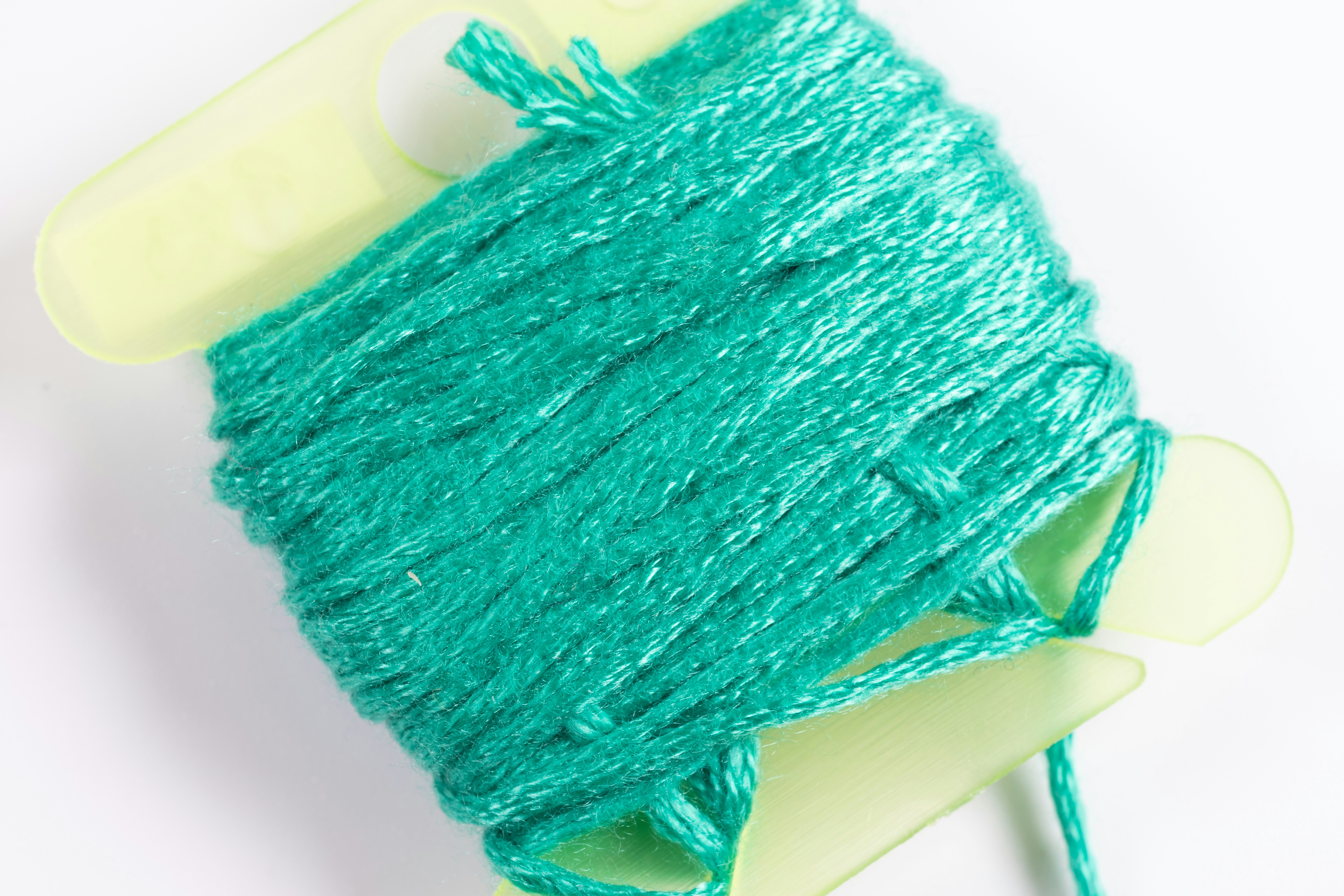 a spool of green thread sitting on top of a white surface