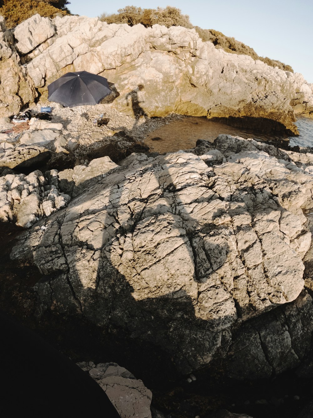 a black umbrella sitting on top of a large rock