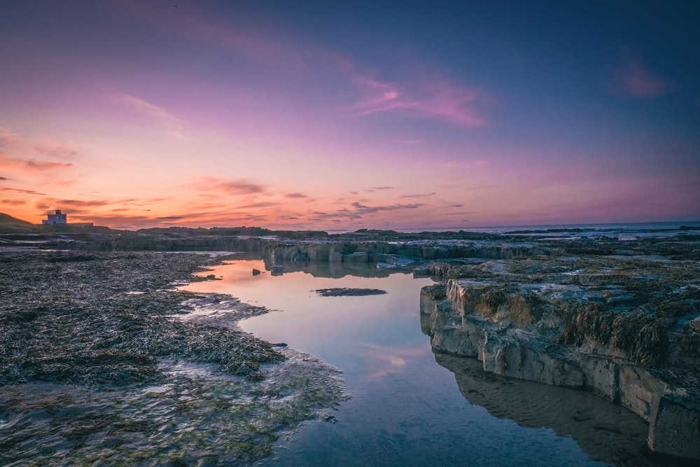 a large body of water sitting next to a rocky shore