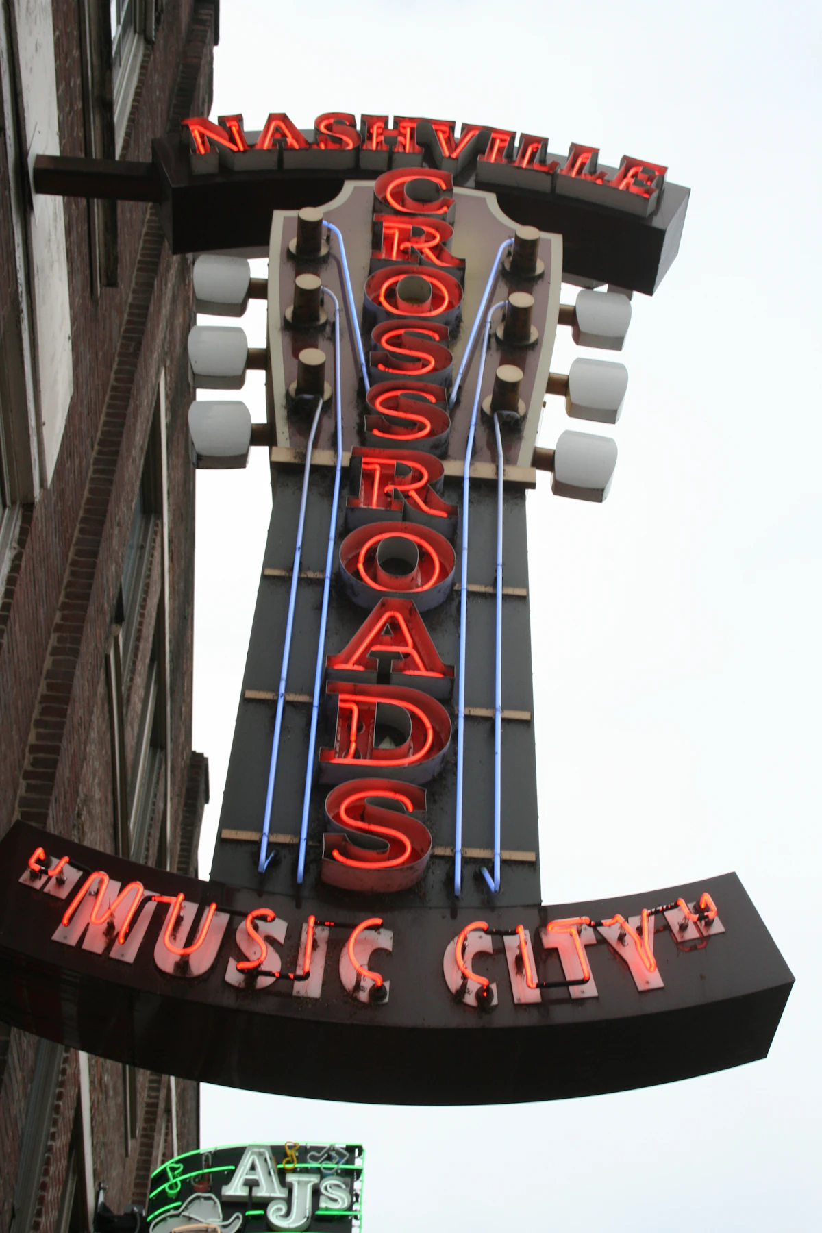 Neon signs and guitars in a music bar window at night