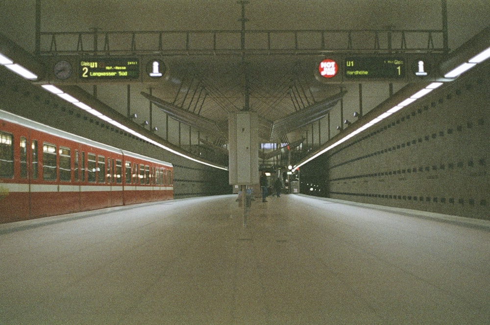 uma estação de metrô com um trem vermelho e branco
