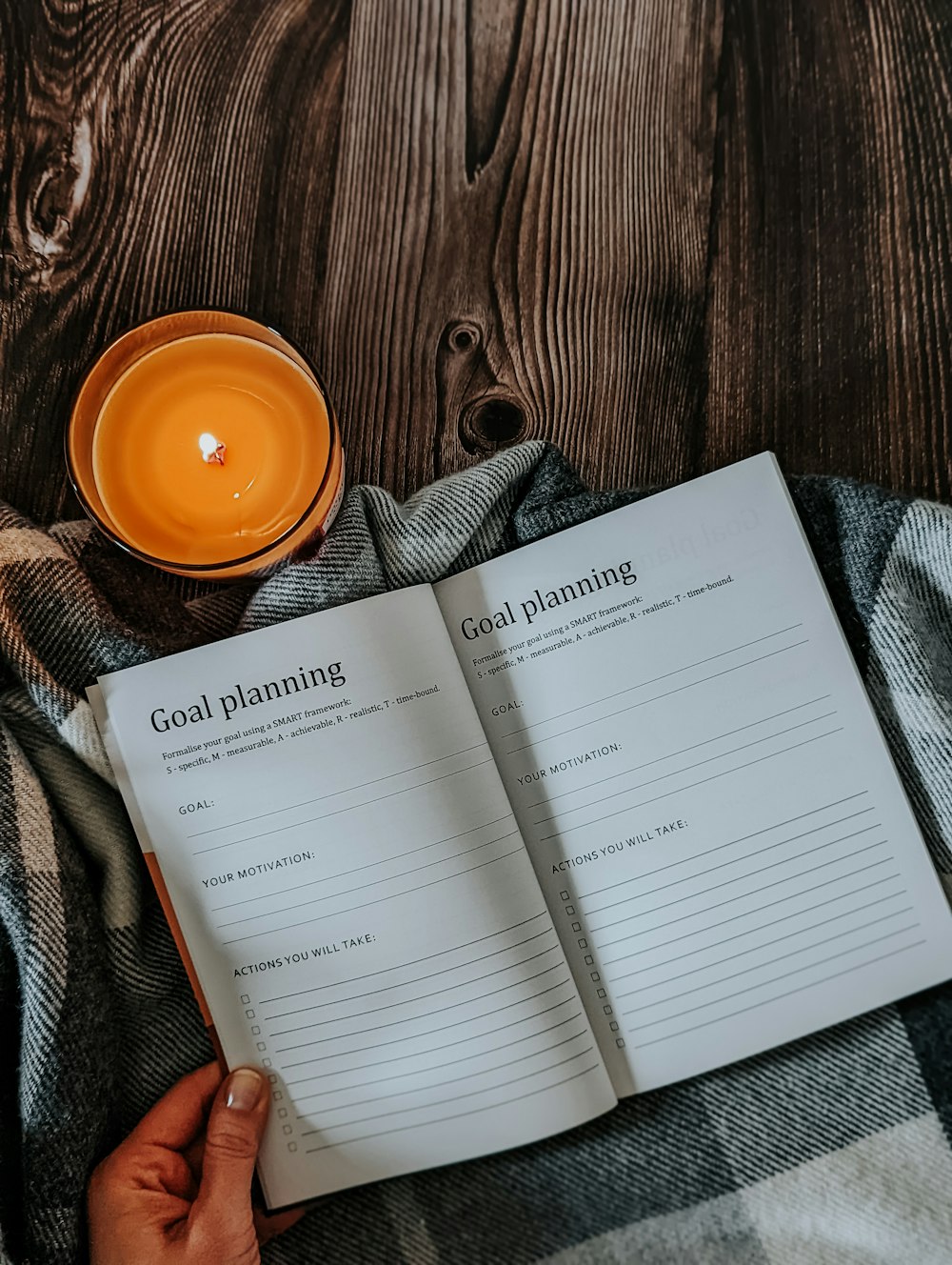 a person holding a book with a candle on top of it