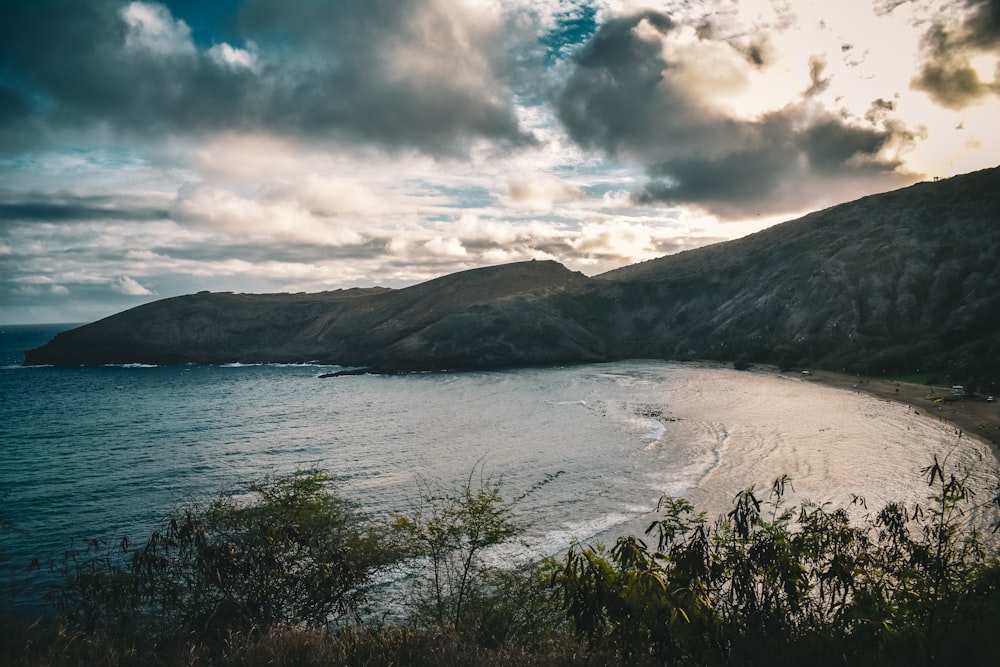 a body of water surrounded by mountains under a cloudy sky