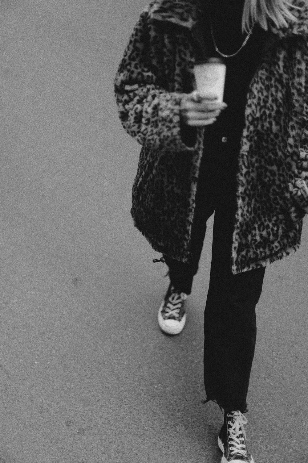 a woman walking down a street while holding a cup of coffee