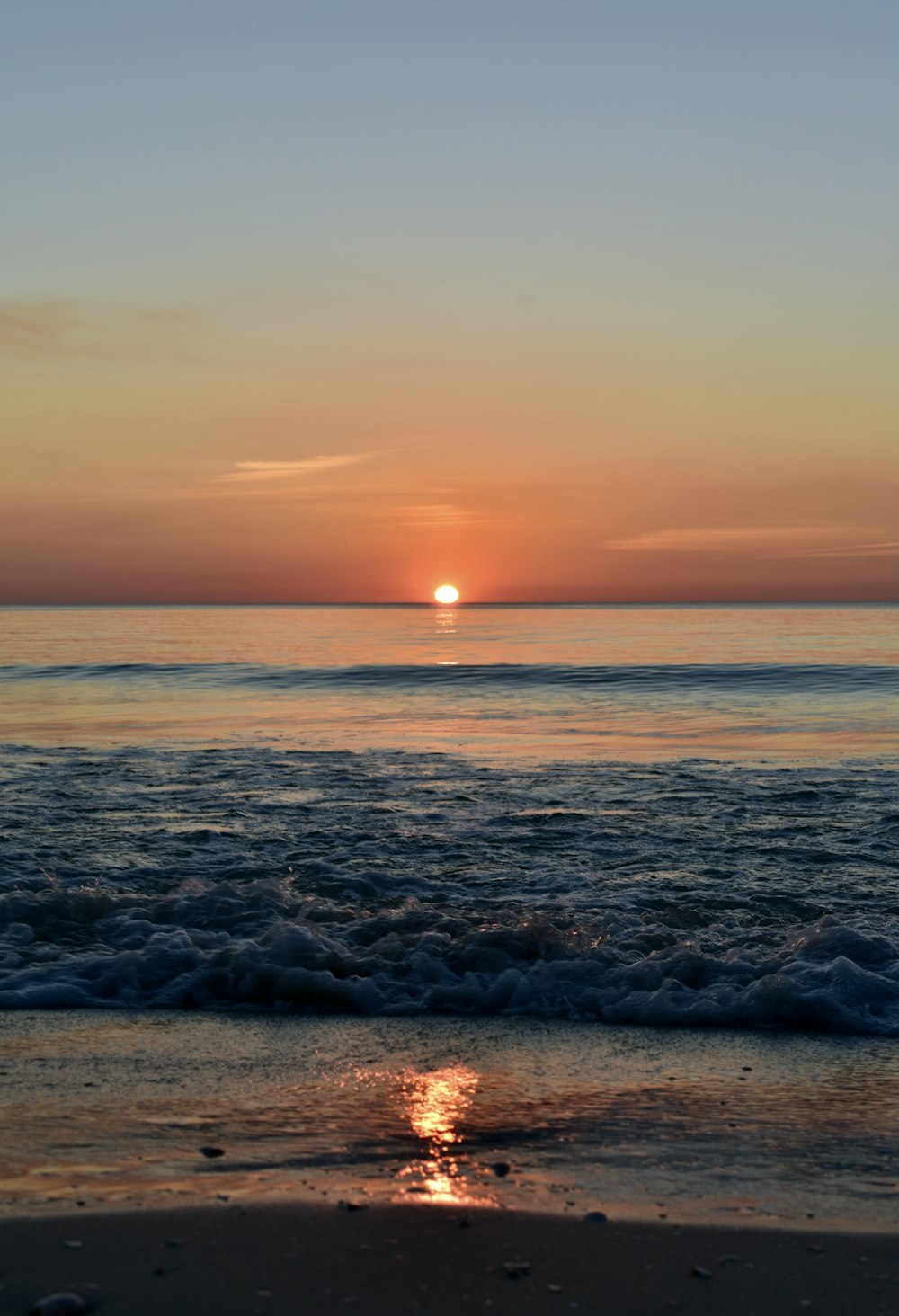 the sun is setting over the ocean on the beach