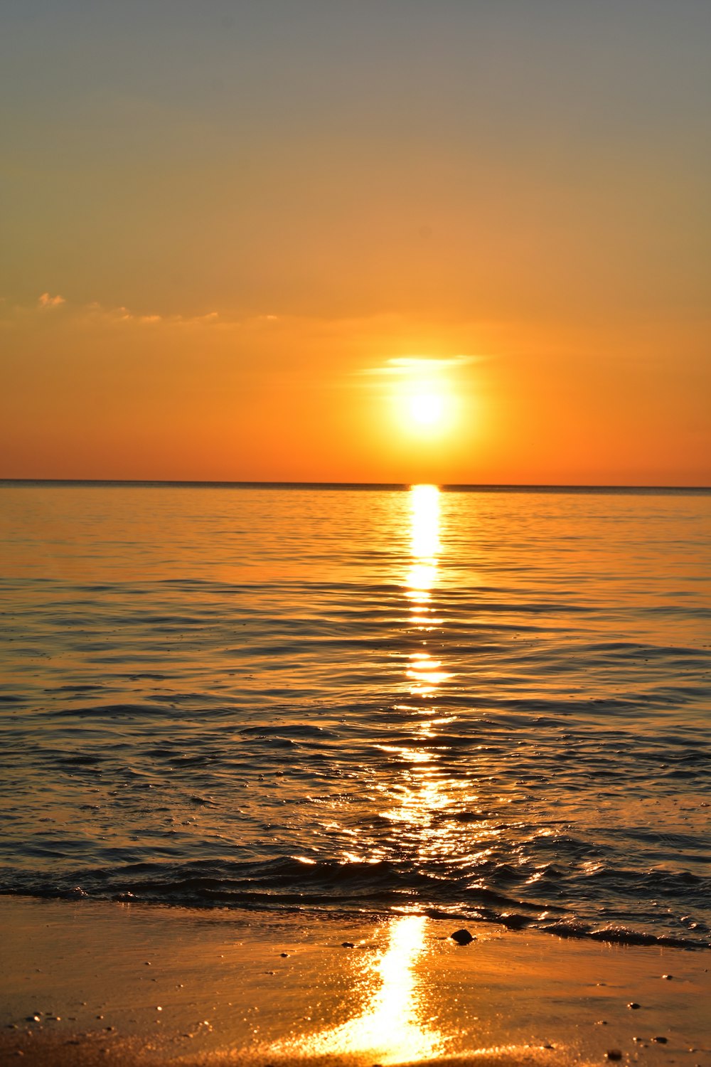 the sun is setting over the water at the beach