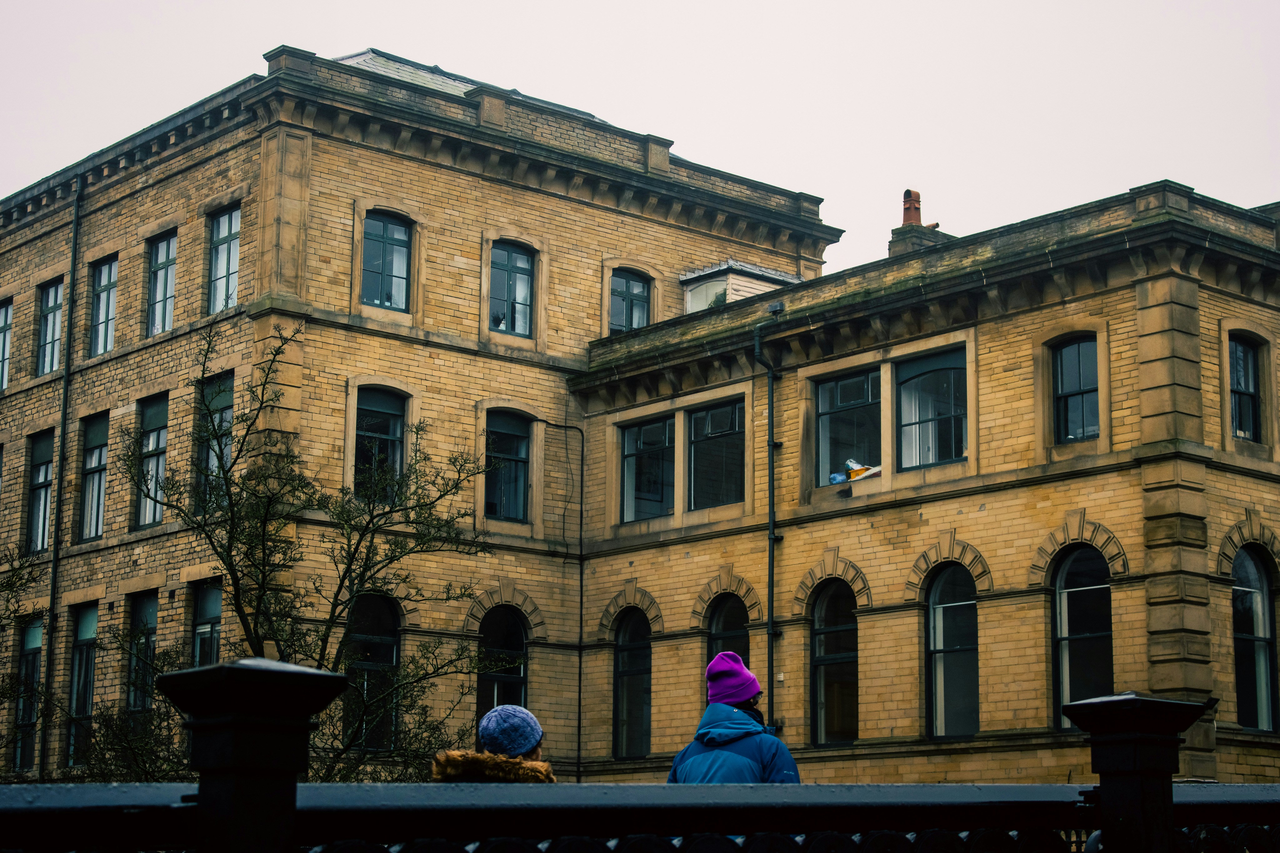 two people sitting on a bench in front of a building