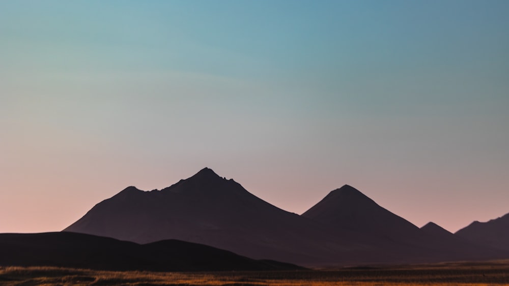 the silhouette of a mountain range against a blue sky