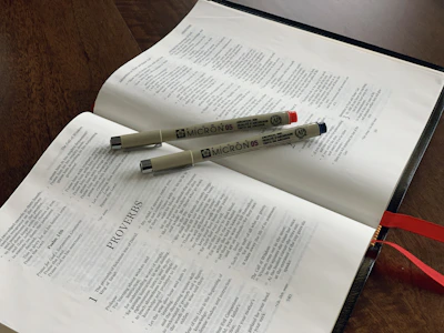 Close-up of an open Bible with a gold pen resting on cream-colored pages.