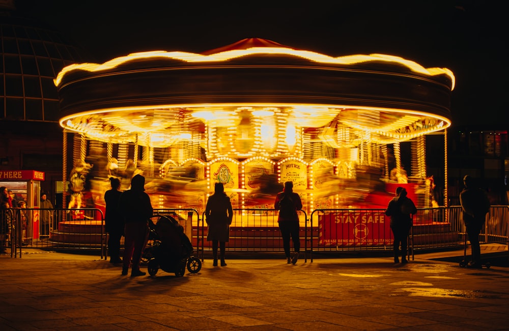 a merry go round at night with people standing around