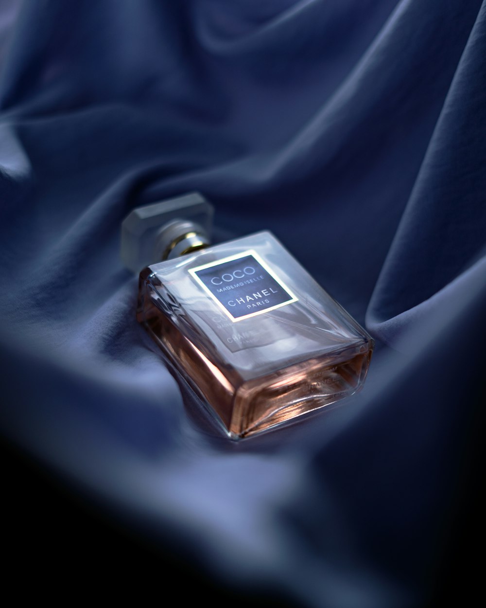 um frasco de perfume sentado em cima de um pano azul