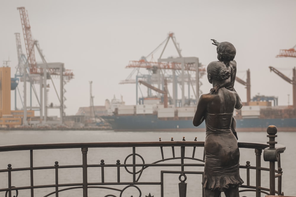 a statue of a woman holding a child near a body of water