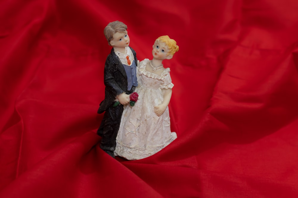 une figurine d’un homme et d’une femme sur un tissu rouge