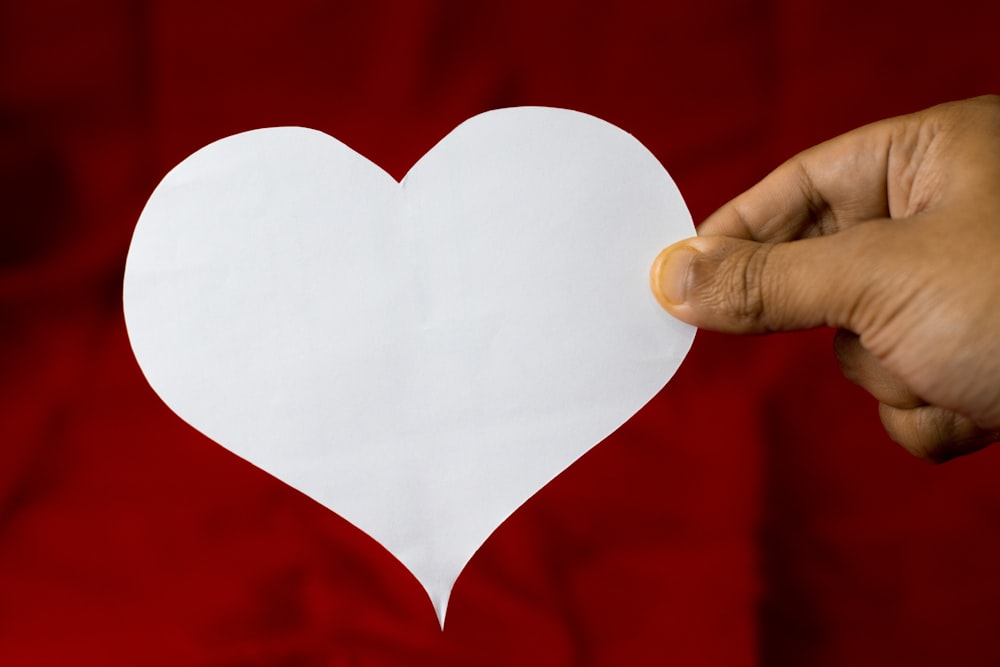 a person holding a piece of paper with a heart cut out of it