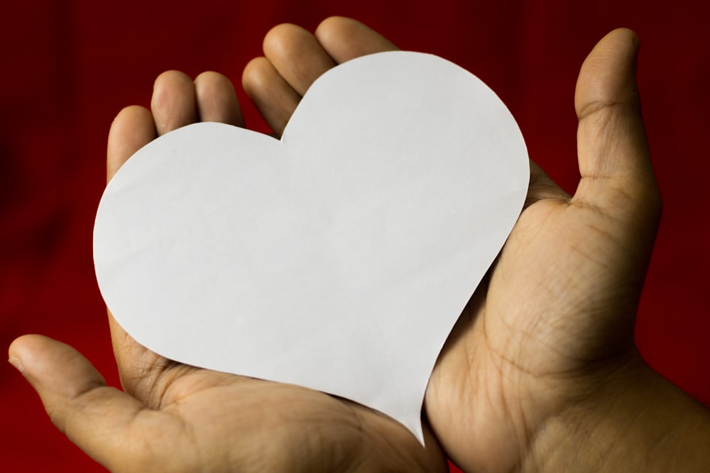 a person holding a paper heart in their hands