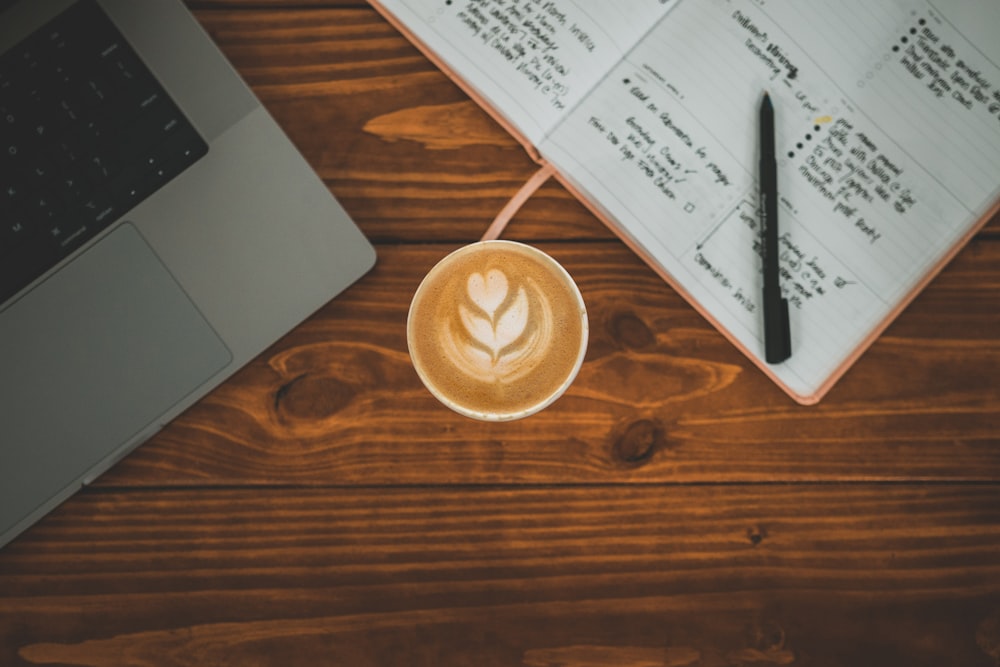 a cup of coffee sitting on top of a wooden table