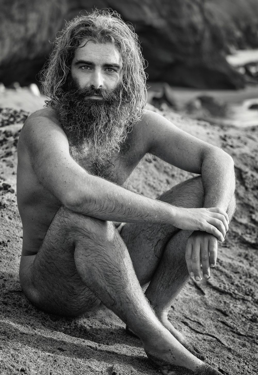 a man with a long beard sitting on the beach