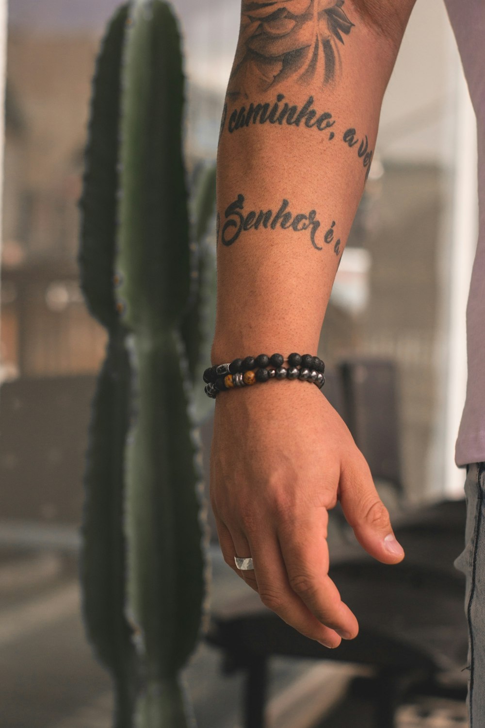 Un hombre con un tatuaje en el brazo junto a un cactus