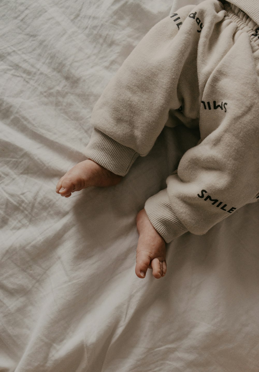 a baby laying on a bed with a white sheet