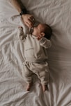 a baby laying on top of a white sheet
