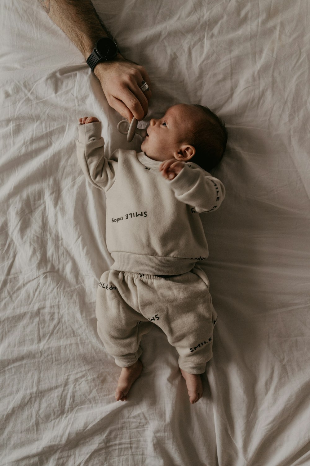 a baby laying on top of a white sheet