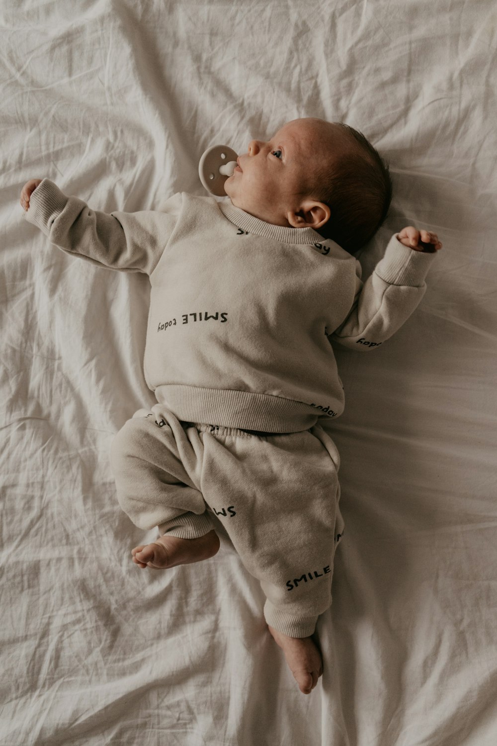 a baby laying on top of a white sheet