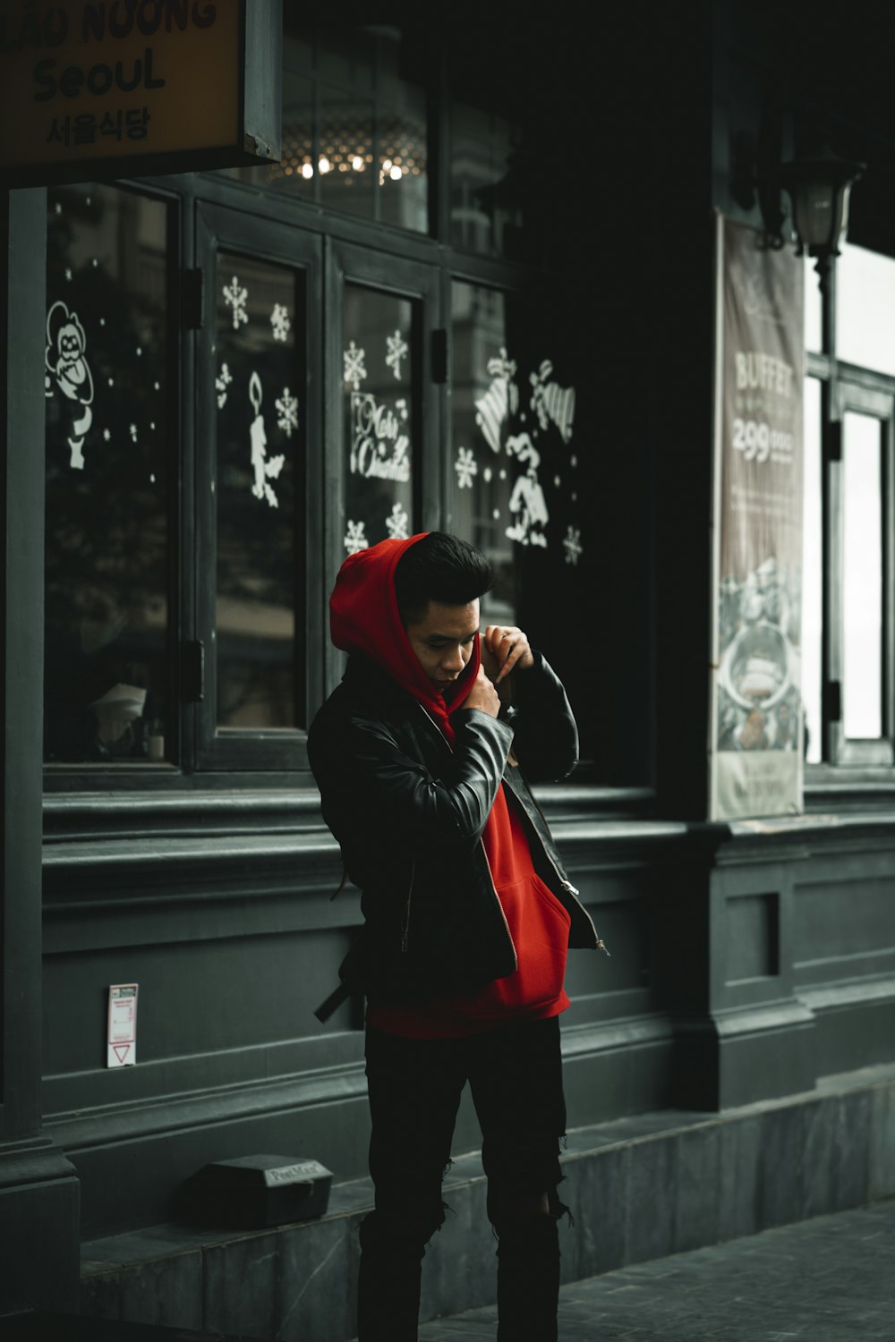a man in a red hoodie standing in front of a building