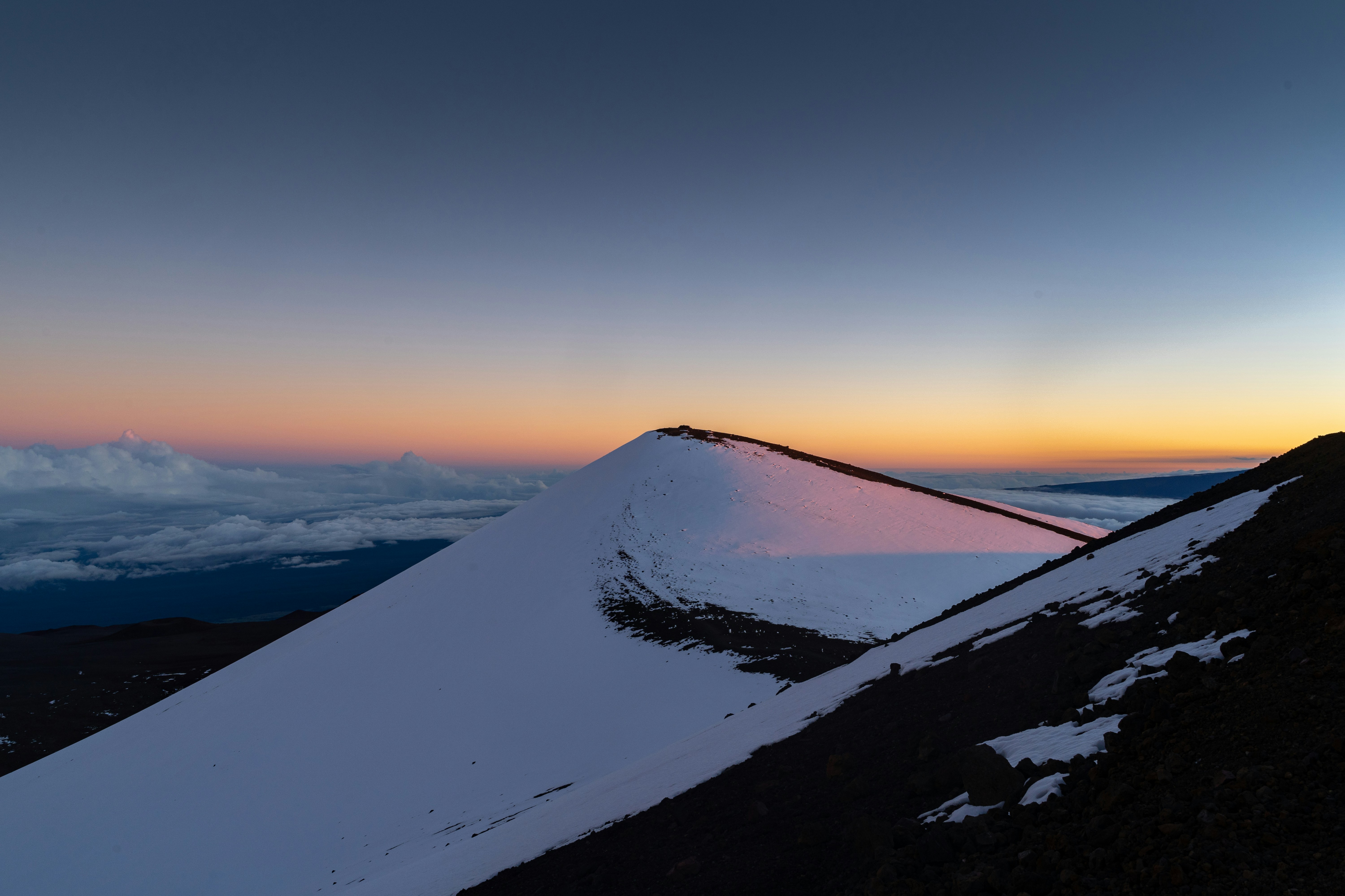 the sun is setting on a snowy mountain