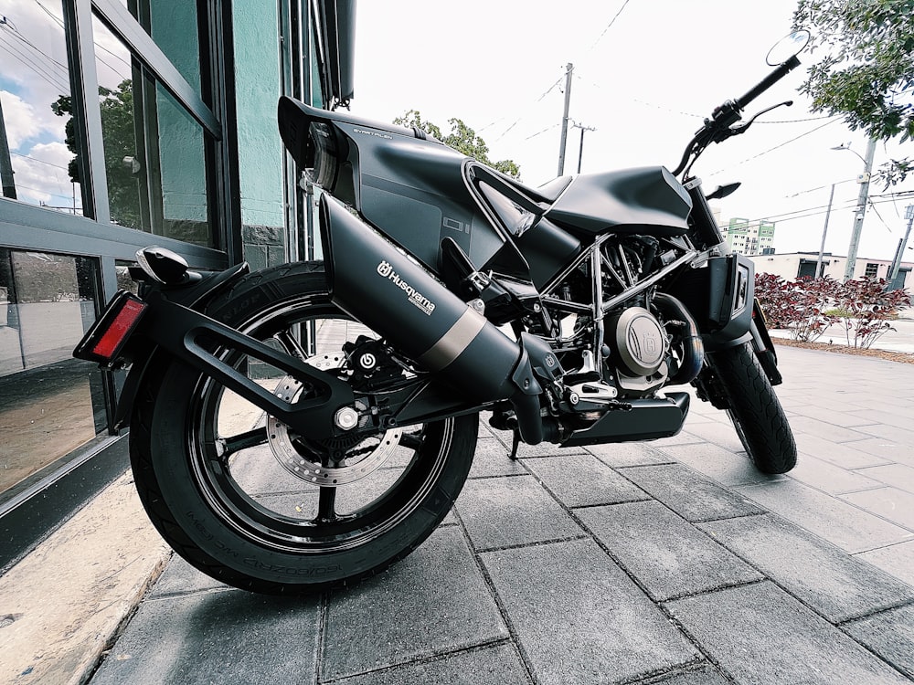 a black motorcycle parked on a sidewalk next to a building