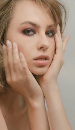 Close-up of a person gently touching their face, highlighting skin texture.