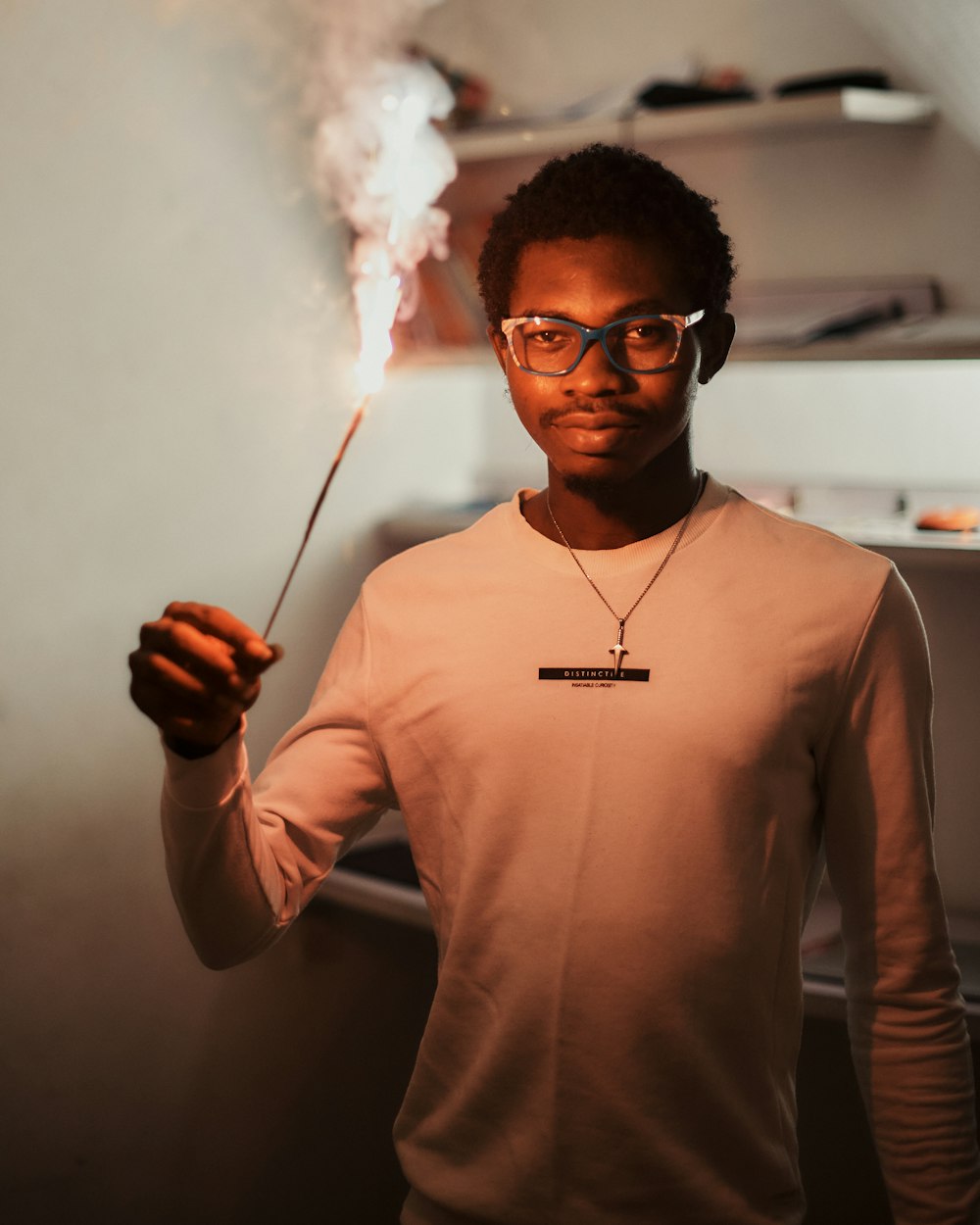 a man in glasses holding a stick with smoke coming out of it