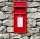 a red post box on a stone wall