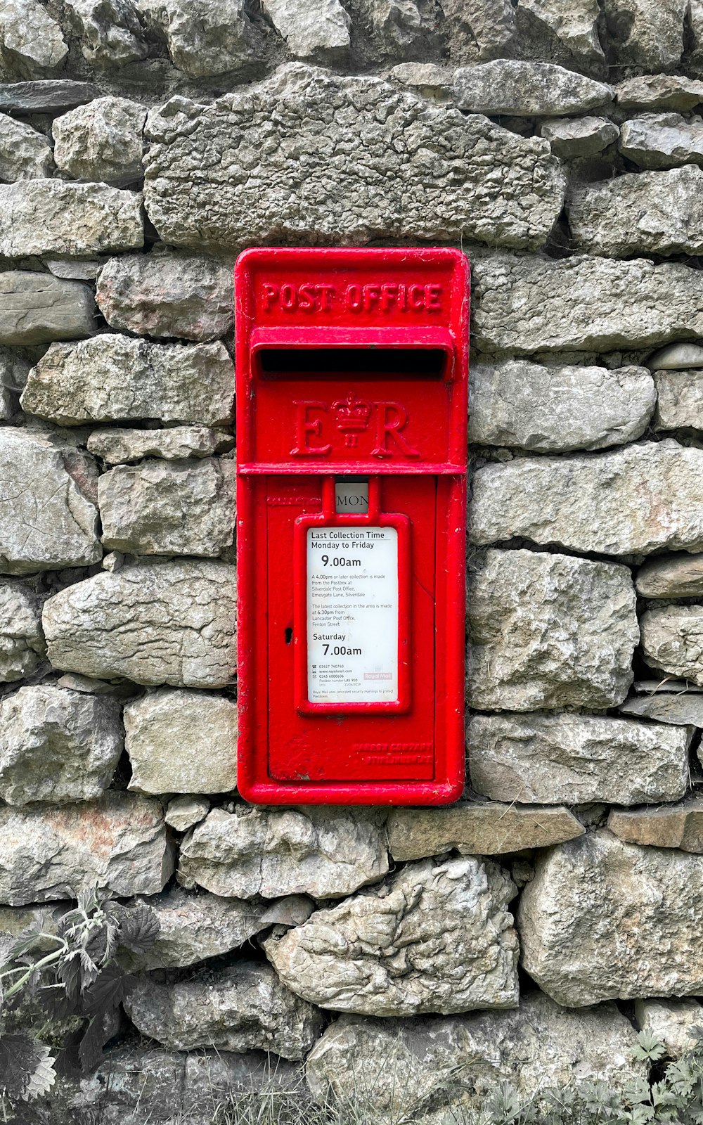 Un buzón rojo en una pared de piedra