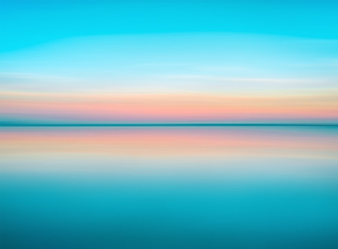 A serene sunset over still waters with gentle pastel colors blending into the horizon.