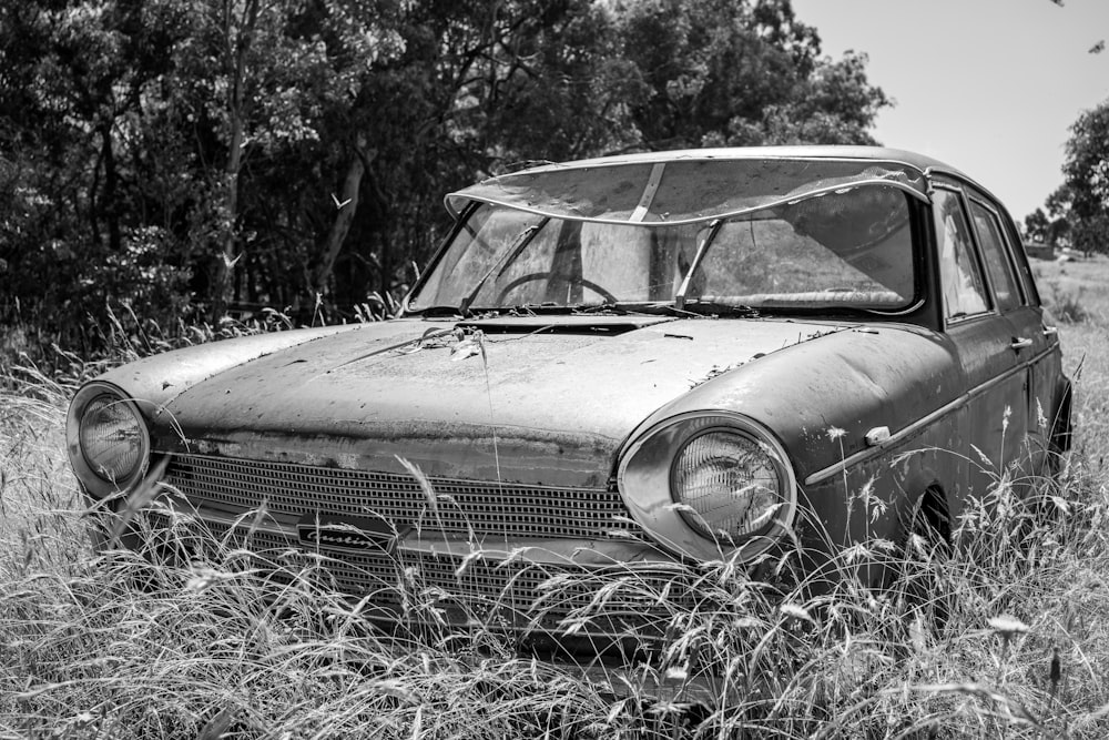 an old car sitting in a field of tall grass