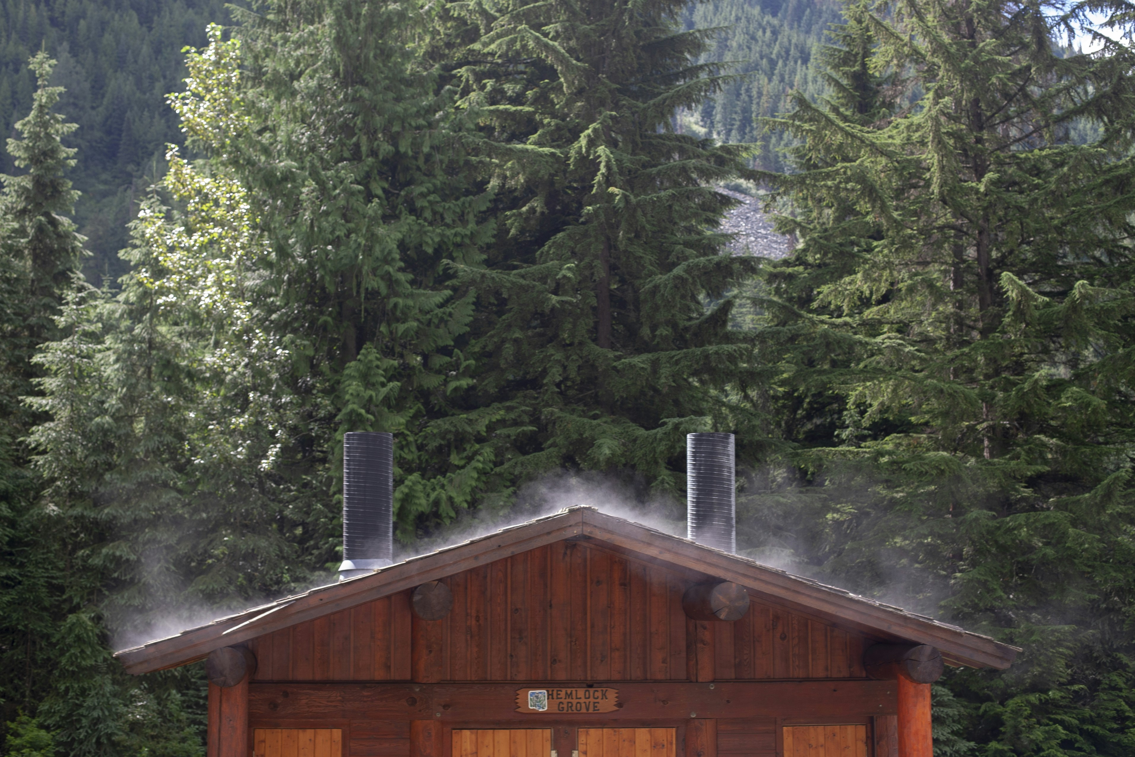 une cabane dans les bois avec de la fumée sortant des cheminées