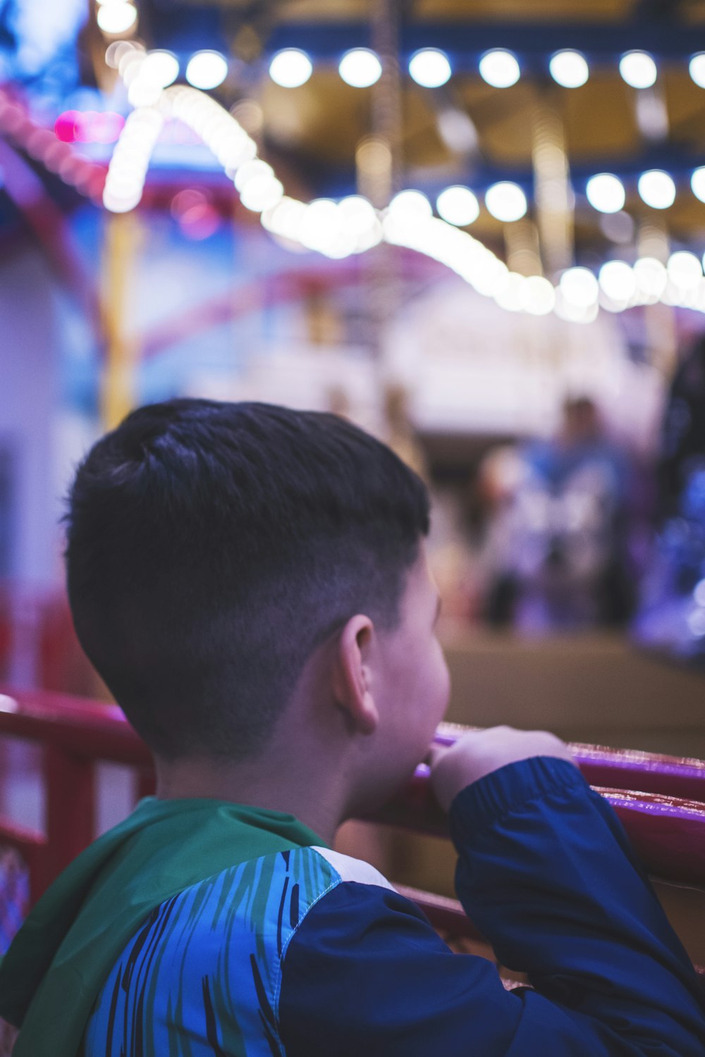 Ein kleiner Junge sitzt auf einer Bank auf einem Karneval