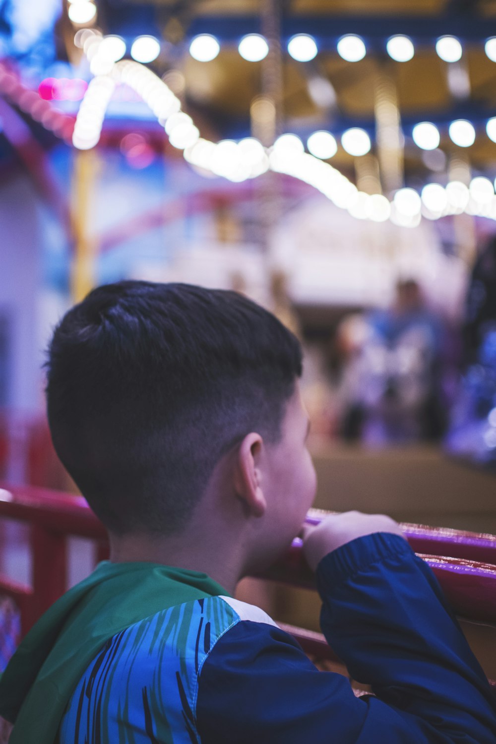 a young boy sitting on a bench at a carnival