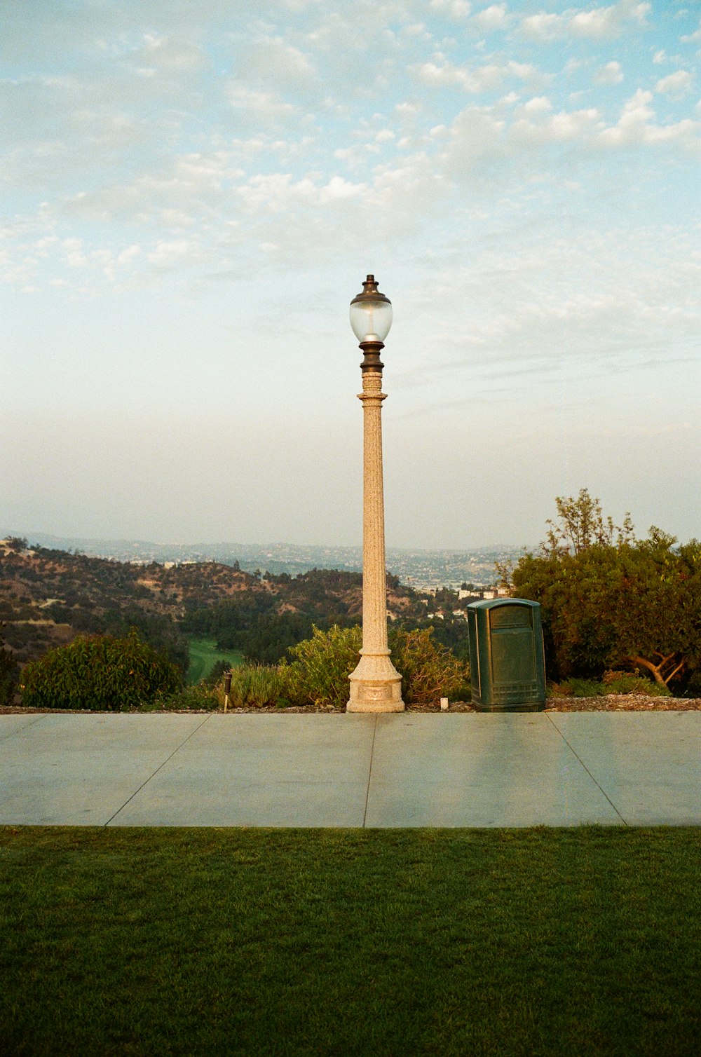 a street light sitting on top of a lush green field