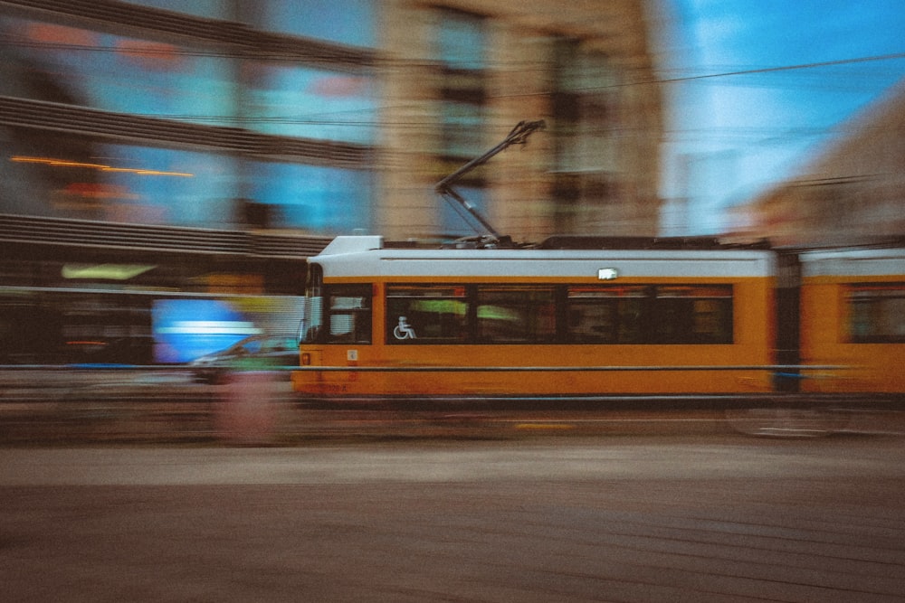 a yellow tram traveling down a street next to tall buildings