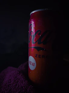 Close-up of a chilled beer can with condensation and neon red lighting in the background