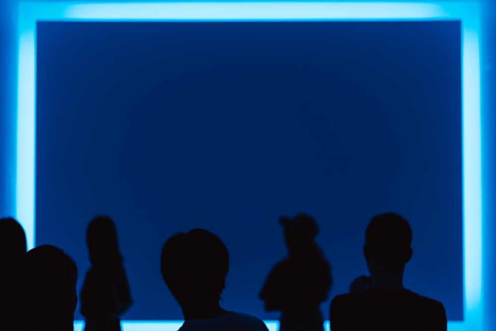 a group of people standing in front of a blue wall