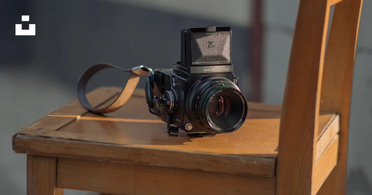 A camera sitting on top of a wooden chair photo – Free Camera Image on ...